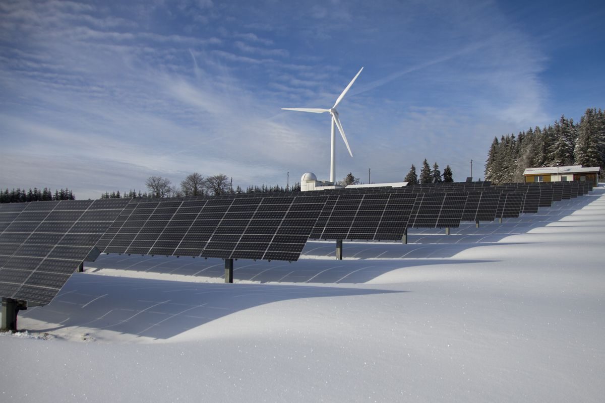 Solar panels covered in snow under a clear winter sky, still generating.